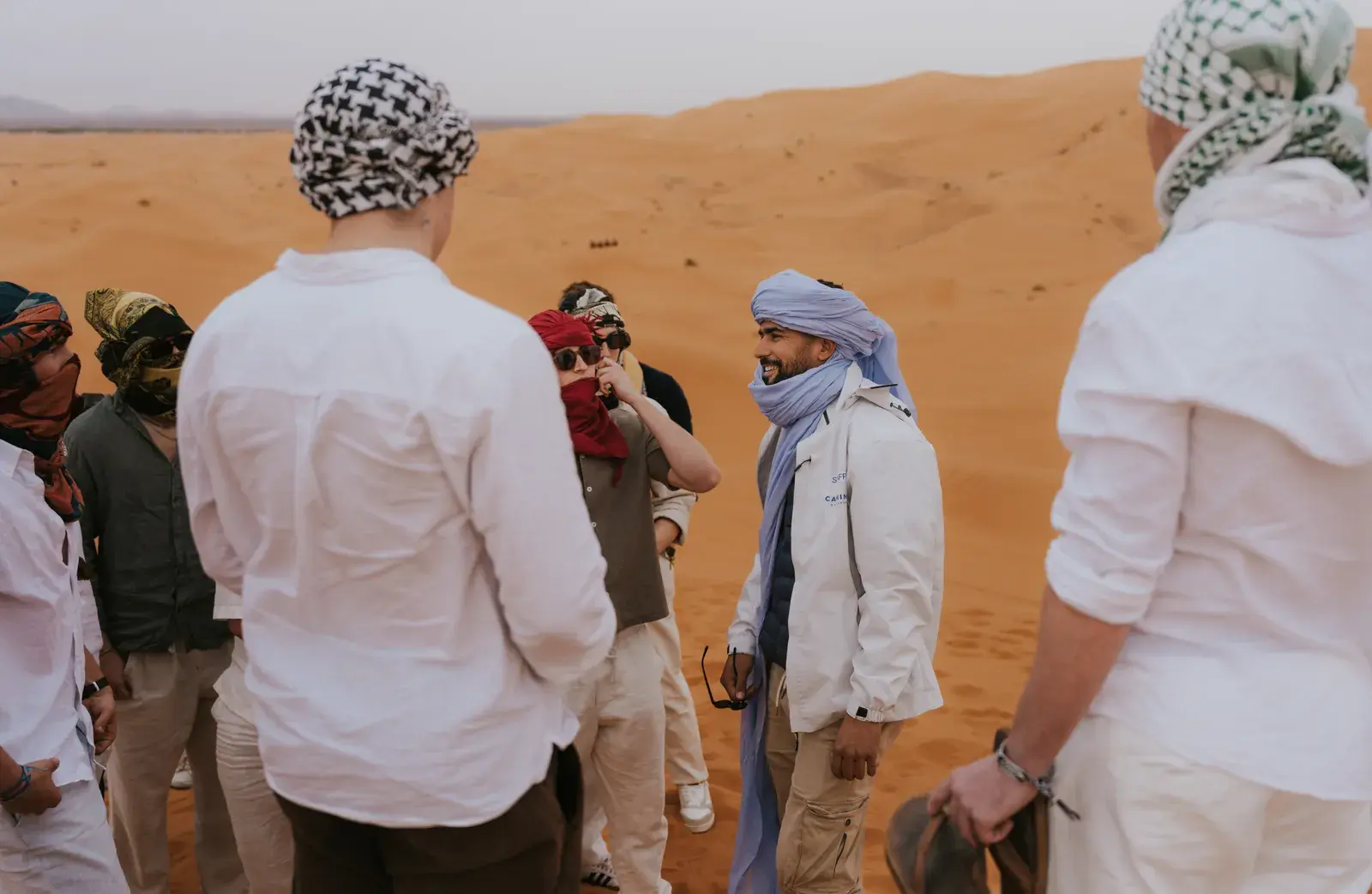 Berber guide sharing stories with students in the dunes