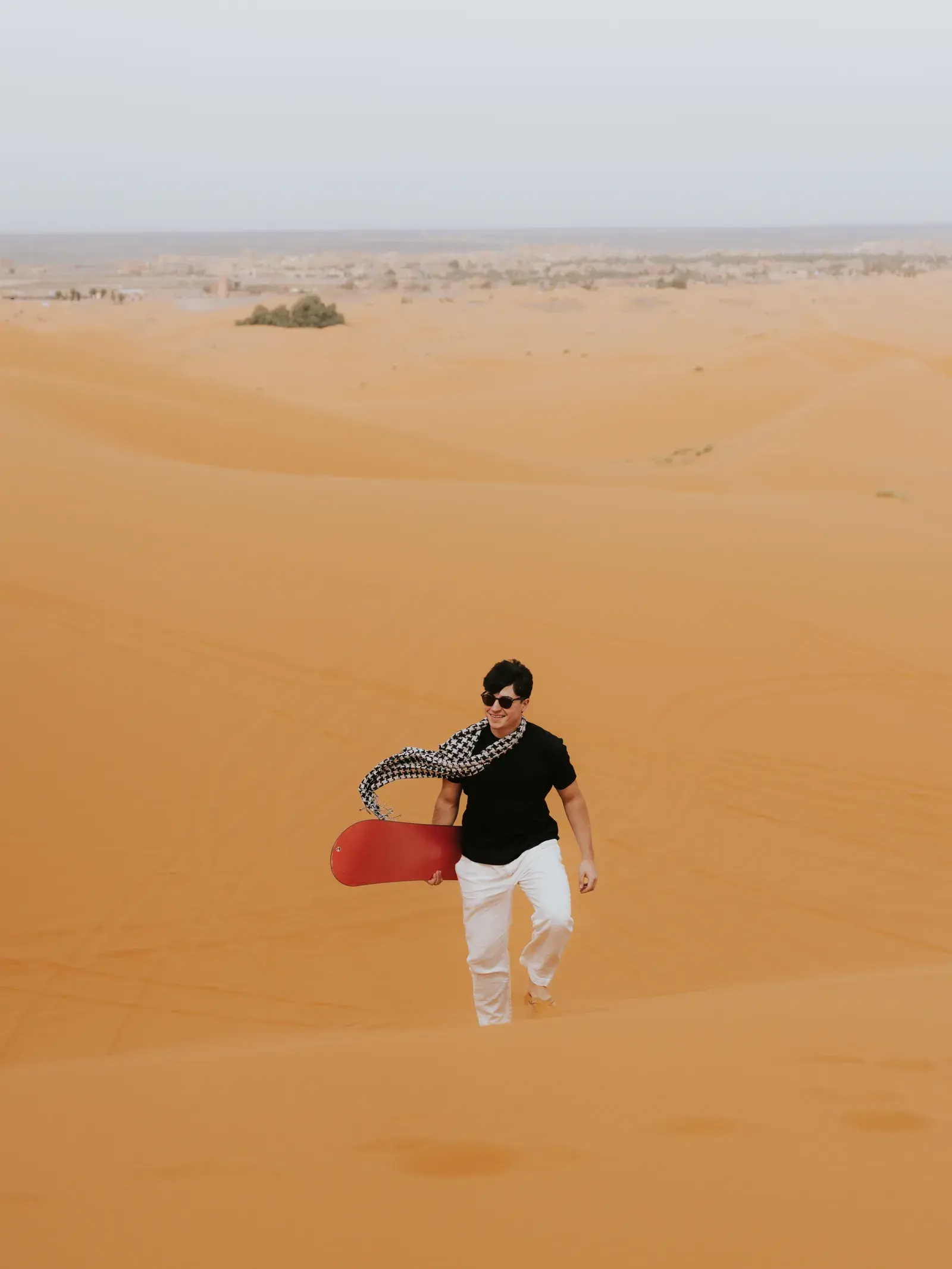 Student sandboarding down the golden Sahara dunes