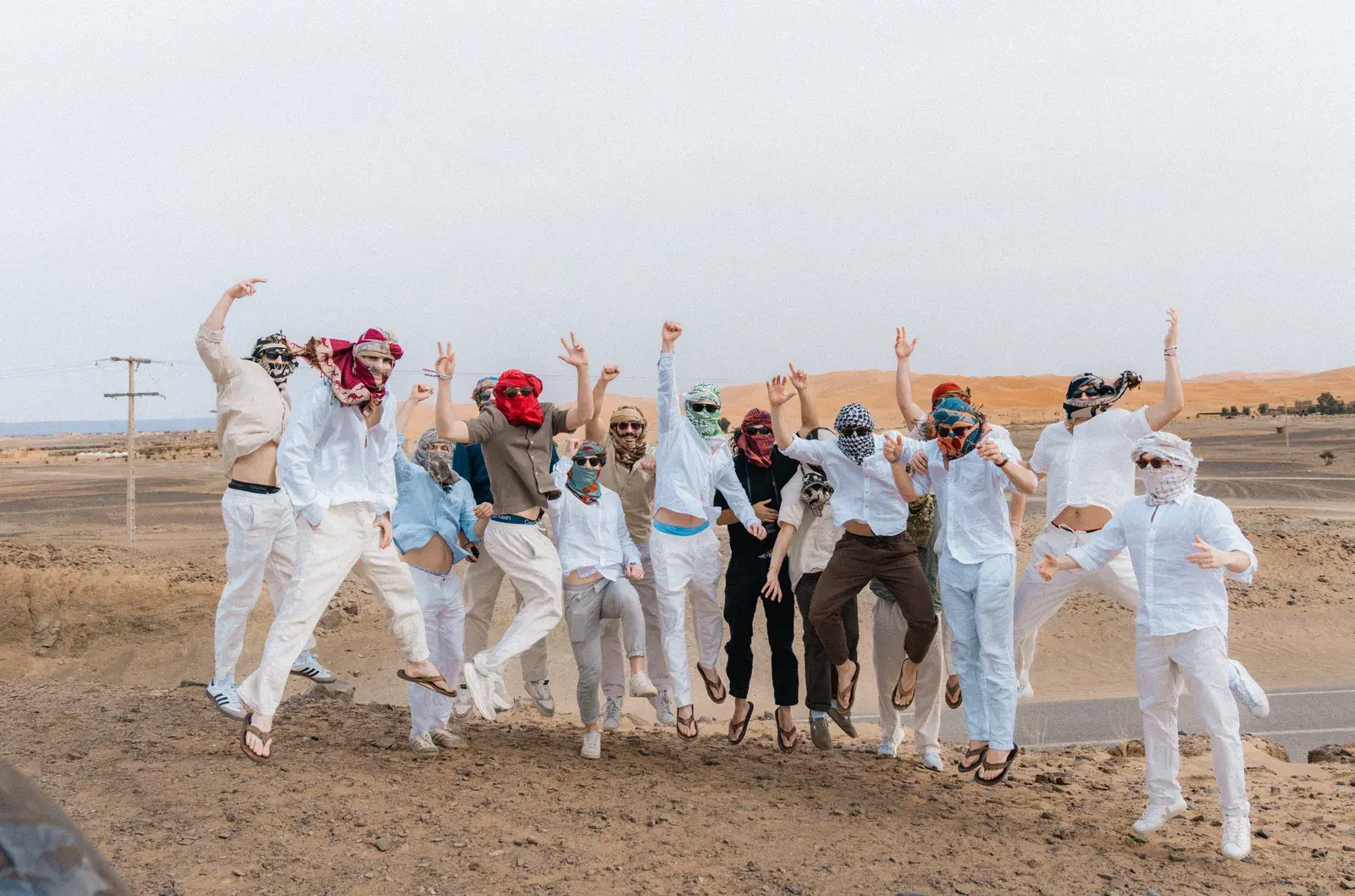 Students jumping together on the Sahara dunes